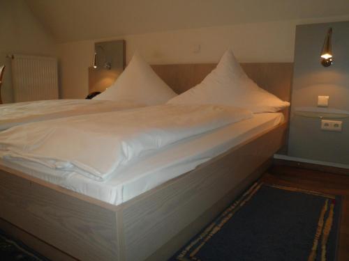 a large bed with white sheets and pillows at Hotel und Gasthof Ritter St. Georg in Erlangen