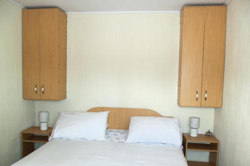 a bedroom with a bed and two wooden cabinets at Acropolis Hostal in La Serena