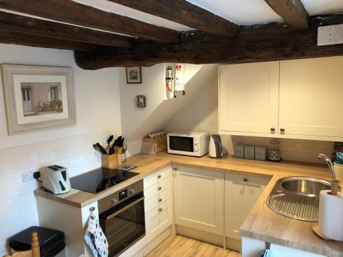 a kitchen with white cabinets and a sink at North Walls cottage in Chichester