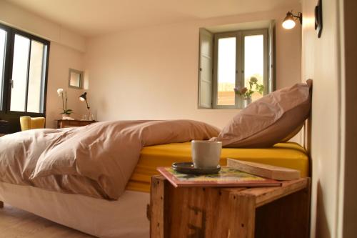 a bedroom with a bed and a table with a cup on it at Les Maillettes in Les Épesses