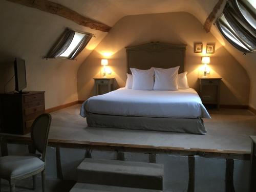 a bedroom with a bed with two lamps and a chair at Hotel L'Aunette Cottage in Chamant