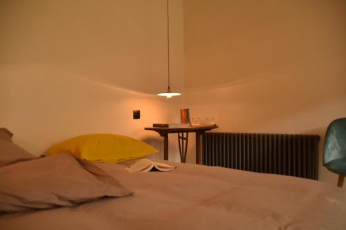 a bedroom with a bed with a yellow pillow and a table at Les Maillettes in Les Épesses
