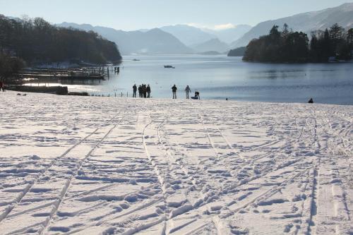 a group of people standing on a snow covered beach at West View in Keswick