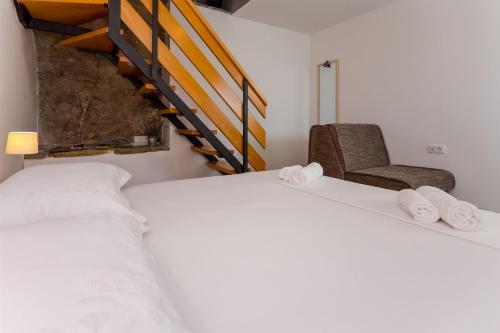 een slaapkamer met een bed, een stoel en een trap bij House Gordana in Gata
