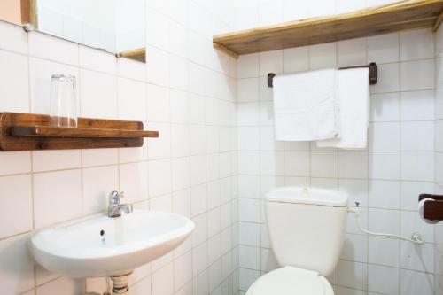 a white bathroom with a toilet and a sink at Auberge de Grand Popo in Grand-Popo