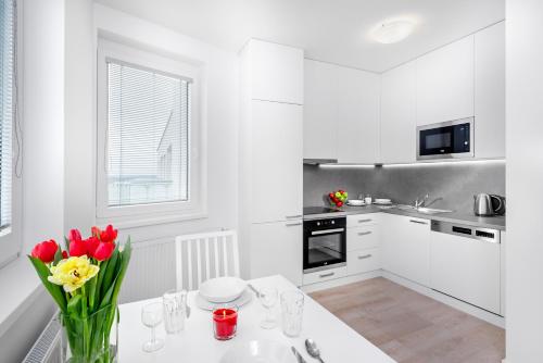 a white kitchen with red flowers in a vase on a table at CityWest Apartments in Prague