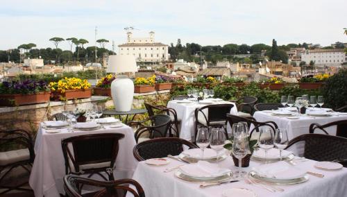 a group of tables with white table cloths on a balcony at Grand Hotel Plaza in Rome