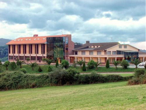 a building with a grass field in front of it at Hotel Royal in Llanera