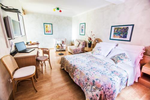 Schlafzimmer mit einem Bett und einem Schreibtisch mit einem Laptop in der Unterkunft Hotel Centro in Torre Pellice