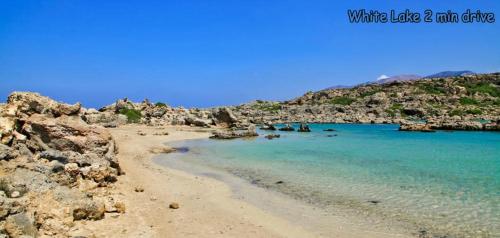 a beach with blue water and a rocky shore at White Lake Holiday House in Elafonisi