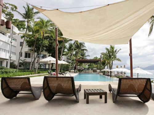 een zwembad in het resort met 2 stoelen en een parasol bij Comfortable Apartment in Caribbean Paradise in Sosúa