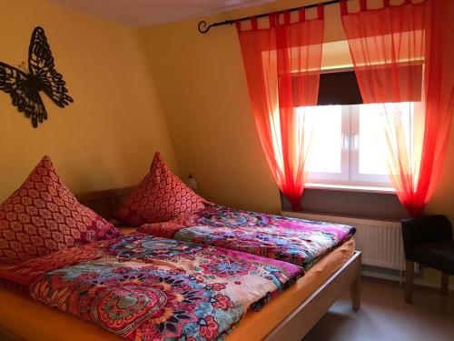 Schlafzimmer mit einem Bett mit roten Vorhängen und einem Fenster in der Unterkunft Ferienwohnungen Perlina Karpat in Bernkastel-Kues