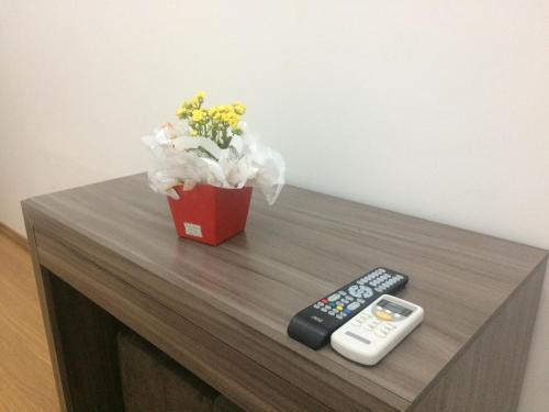 a vase of flowers and a remote control on a table at Hotel St. Daniel in Guarulhos