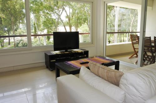 a living room with a white couch and a tv at Green Park en Punta del Este in Punta del Este