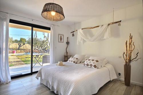 a bedroom with a white bed and a large window at La Villa Aux Oliviers in Flayosc