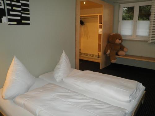a bed with a teddy bear in a bedroom at Hotel und Gasthof Ritter St. Georg in Erlangen