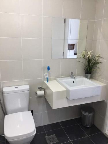 a bathroom with a sink and a toilet and a mirror at Meridin Medini Muslim Condo in Nusajaya