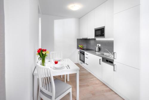 uma cozinha branca com uma pequena mesa e cadeiras brancas em CityWest Apartments em Praga