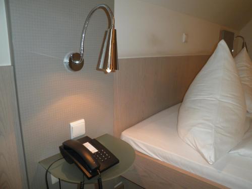 a phone on a table next to a bed with a lamp at Hotel und Gasthof Ritter St. Georg in Erlangen