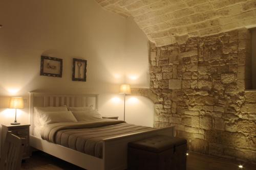 1 dormitorio con cama y pared de piedra en DeShome Guest House, en Bari