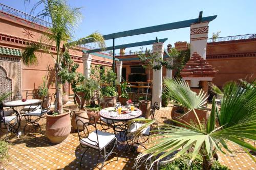 d'une terrasse avec des tables, des chaises et des palmiers. dans l'établissement Riad Jnane Mogador, à Marrakech