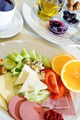 a plate of food with cheese and fruit on a table at Helen Hotel in Canakkale