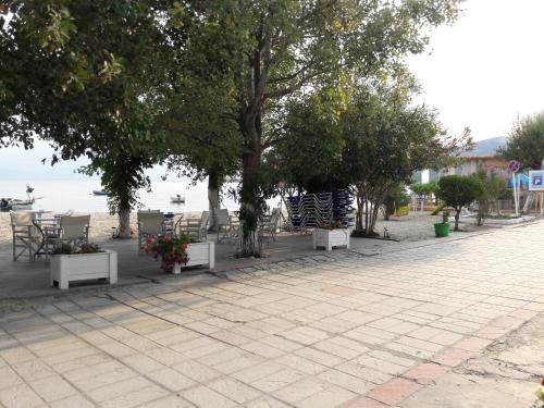 a sidewalk with tables and chairs and trees on the beach at Hotel Prinos in Prinos