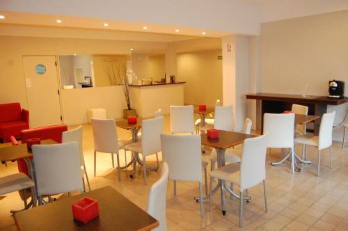 un restaurante con mesas, sillas blancas y una barra en Horizonte Hotel, en Mar del Plata