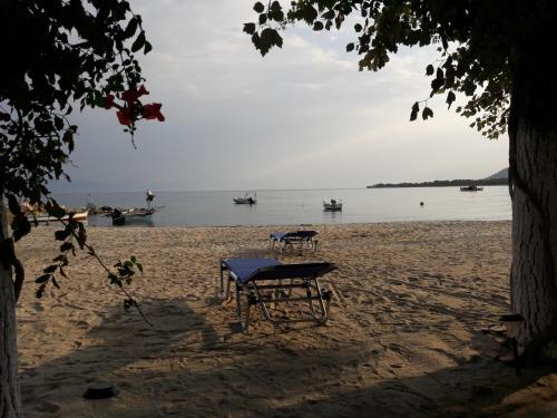 a picnic table on a beach with boats in the water at Hotel Prinos in Prinos