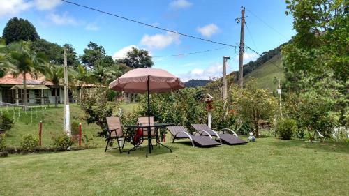 a table and chairs and an umbrella in a yard at Casa Amarela da Uruçu in Aracê