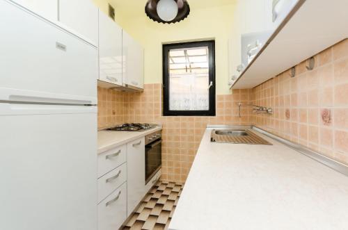 a kitchen with white cabinets and a window at Apartments Dragutin in Medulin