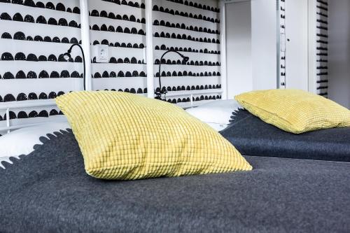 two beds with yellow pillows on them in a room at Hostel Café Koti in Rovaniemi