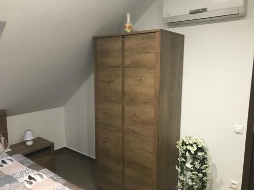 a wooden cabinet in a bedroom next to a bed at Győri vendégház in Demjén