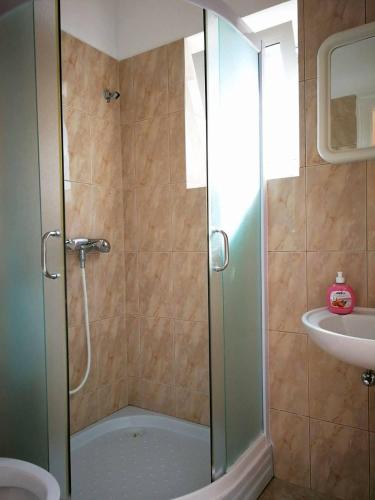 a shower with a glass door next to a sink at Apartmani Rija 3 in Pag