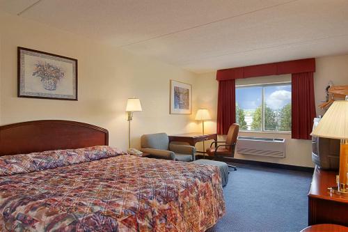 a hotel room with a bed and a desk and a window at Super 8 by Wyndham Manchester Airport in Manchester