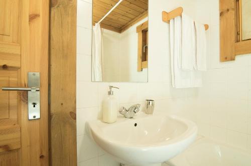 Baño blanco con lavabo y espejo en Chalé | Penhas da Saúde - Serra da Estrela, en Penhas da Saúde