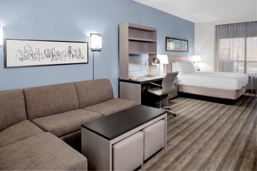 a hotel room with a couch and a bed and a desk at Hyatt House Dallas Lincoln Park in Dallas