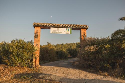 una puerta en un camino de tierra con un letrero de calle en Agroturismo Ecologico el Cortijillo en Luque