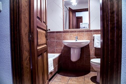 uma casa de banho com um lavatório, um WC e um espelho. em Hostal Goya II em Carbonero el Mayor