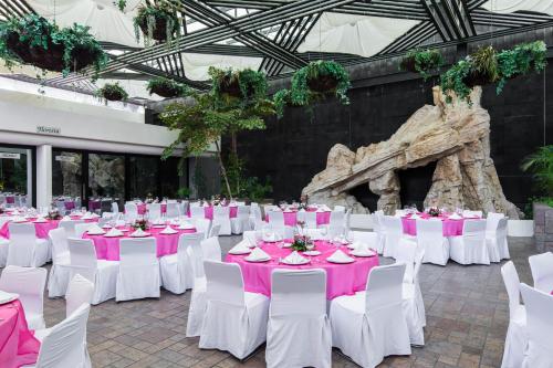 a group of tables and chairs with pink and white table settings at Wyndham Executivo Culiacan in Culiacán