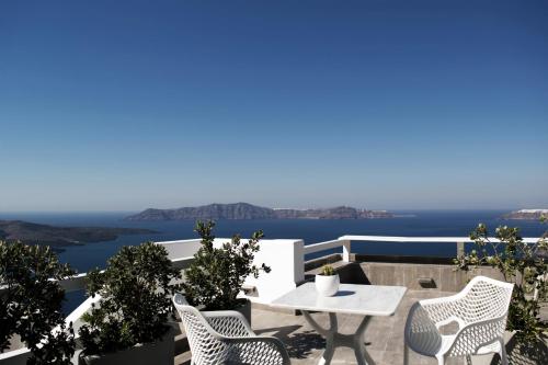 a patio with a table and chairs and the ocean at Hotel Thireas in Fira