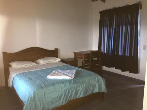 a bedroom with a bed and a table and a window at Cabinas Lindo Horizonte in San Pedro