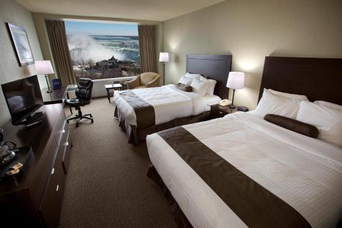 a hotel room with two beds and a window at The Oakes Hotel Overlooking the Falls in Niagara Falls