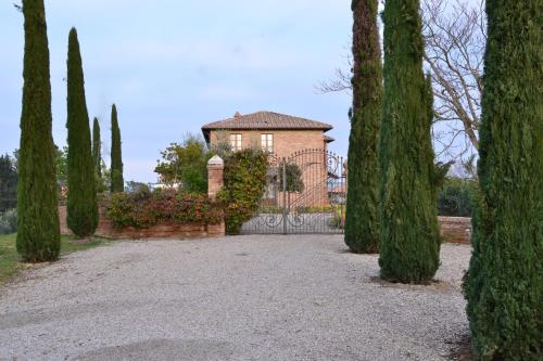 a house with a gate in a garden with trees at Agriturismo Sanguineto in Acquaviva
