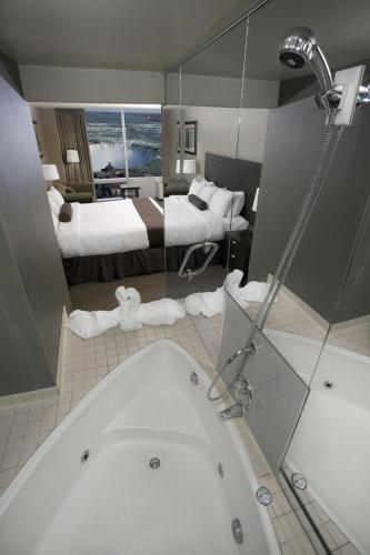 a bathroom with a tub and a bedroom with two beds at The Oakes Hotel Overlooking the Falls in Niagara Falls