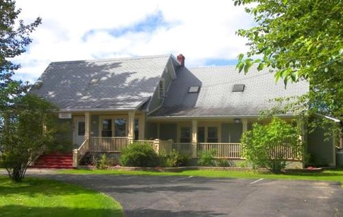 a green house with a porch and a yard at Carriage House Inn Four and a Half Stars in Grand Falls -Windsor