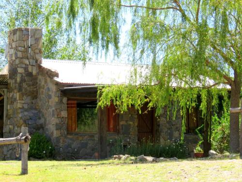 a stone house with a tree in front of it at Estancia Altos del Durazno in Estancia Grande
