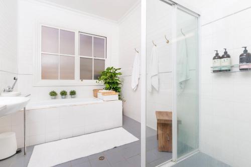 baño blanco con ducha y lavamanos en Jetty House en Coffs Harbour