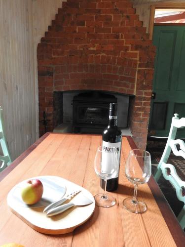 a bottle of wine and an apple on a wooden table at Cooks Cottage in McLaren Vale