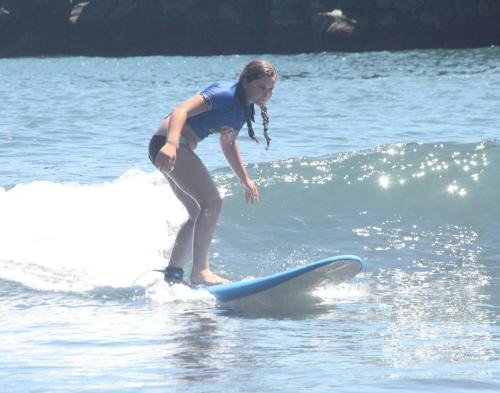 a young girl riding a wave on a surfboard in the water at Hotel Vila Bela in Porto da Cruz